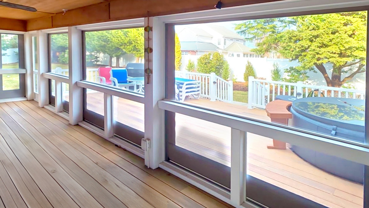 Interior view of motorized vinyl porch enclosure with crystal clear panels enclosing a deck and hot tub, professional porch enclosure installation in Rehoboth DE.