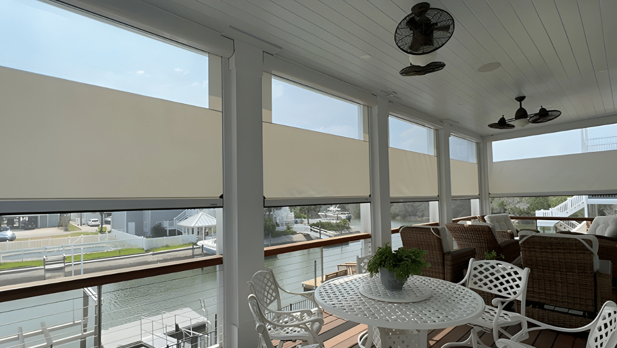 Covered waterfront porch in Delaware with multiple motorized shade screens partially lowered overlooking canal views.