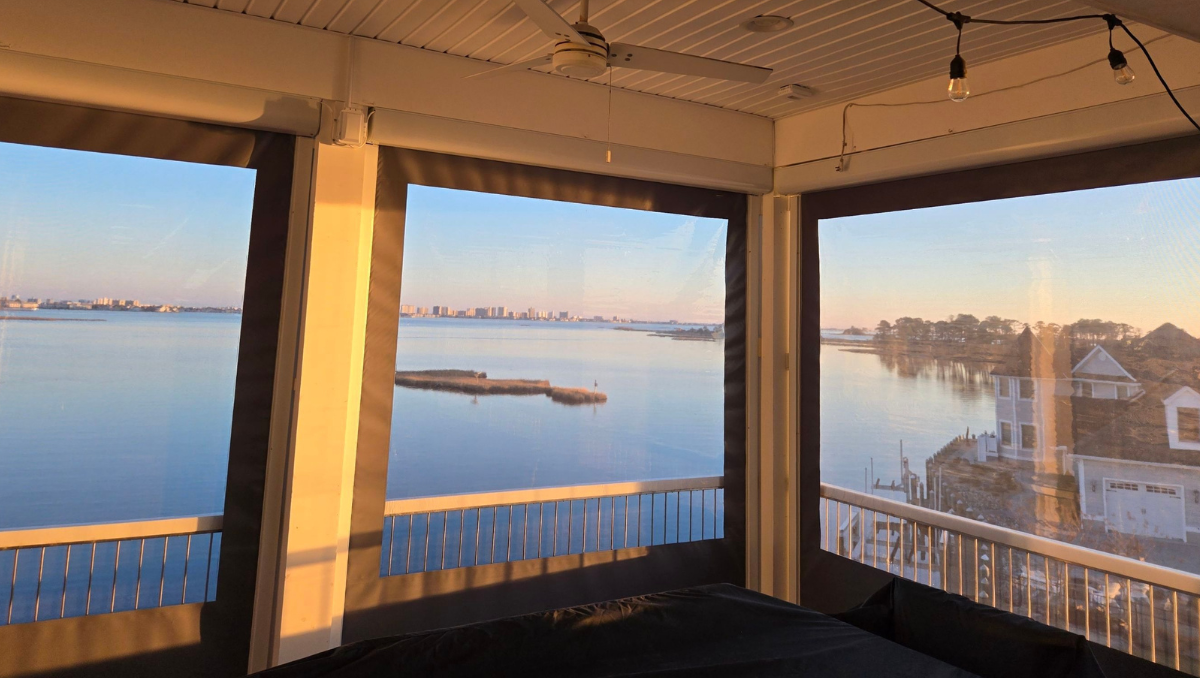 Waterfront outdoor dining area protected by motorized vinyl patio enclosures during sunset on the Eastern Shore