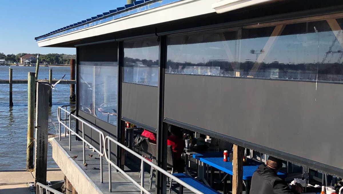 Commercial restaurant patio with motorized screen enclosures protecting outdoor dining along the waterfront