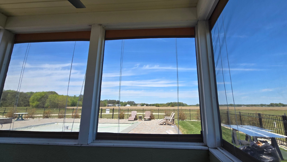Interior view of manual vinyl porch enclosures installed on a screened porch in Milton Delaware with clear countryside views