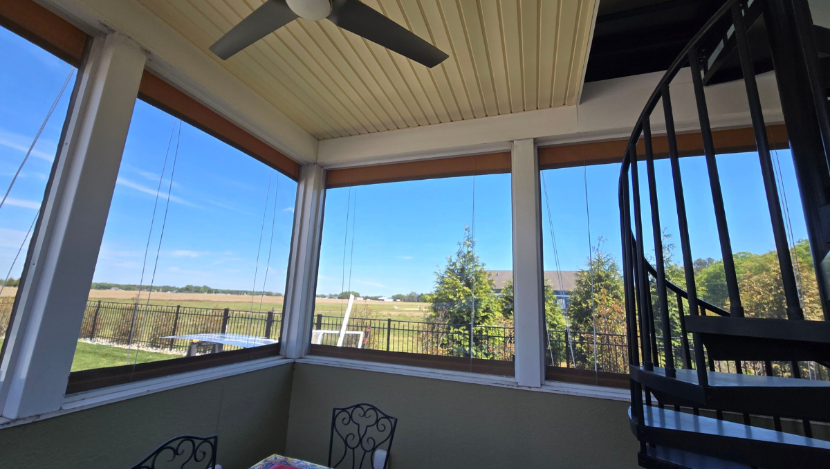 Manual vinyl porch enclosure installation in Milton Delaware featuring clear vinyl panels and outdoor spiral staircase