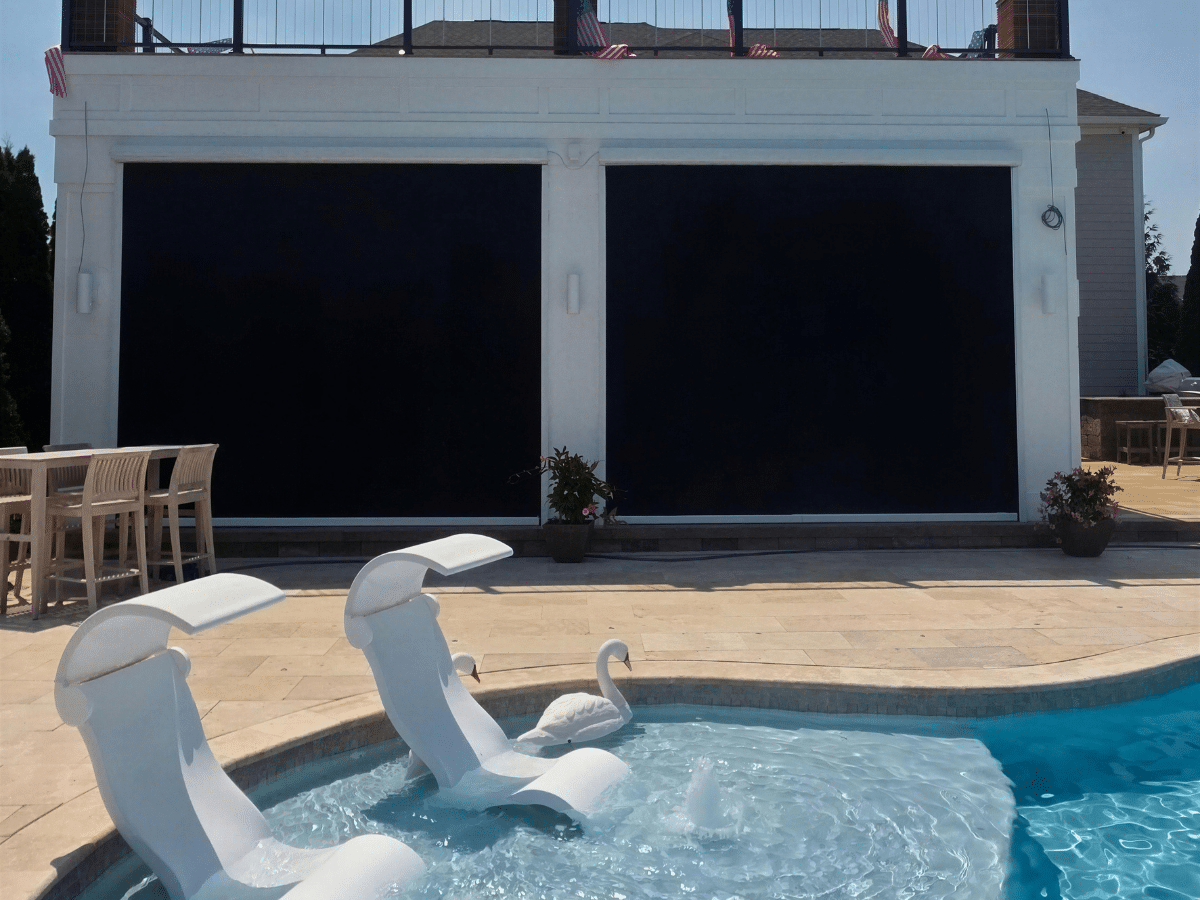 Motorized solar and privacy screens installed on a luxury home overlooking a swimming pool in Lewes, Delaware.