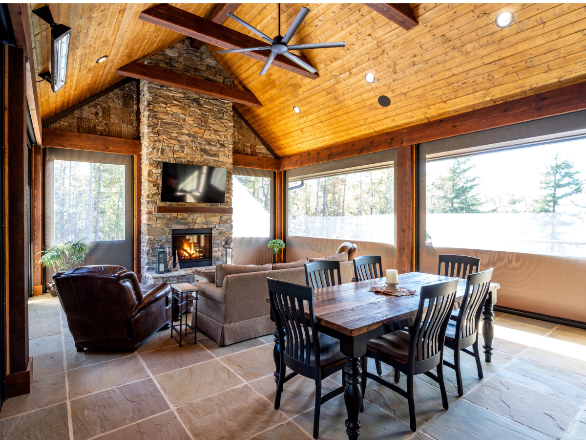 Spacious outdoor living room with fireplace, dining area, and clear vinyl enclosure creating year-round comfort.