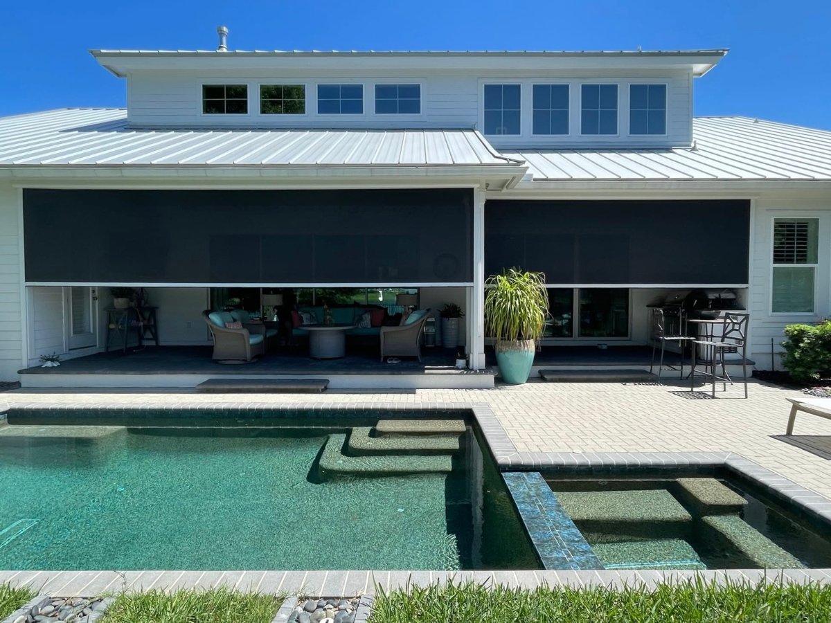 Motorized porch screens installed on a backyard patio overlooking a swimming pool to create a comfortable outdoor living space.
