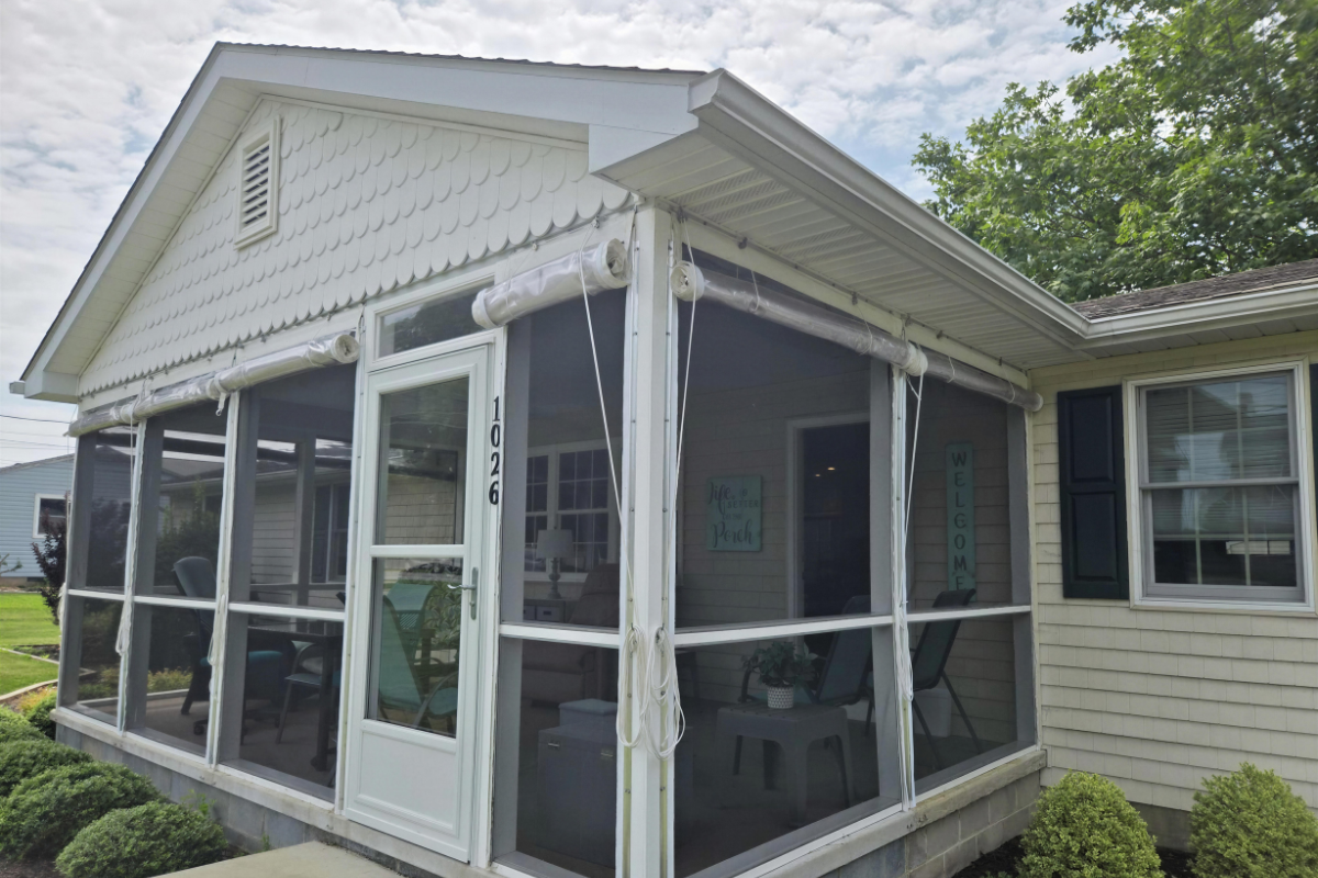 Screened porch enclosed with clear roll-up vinyl panels, providing weather protection while maintaining outdoor views.